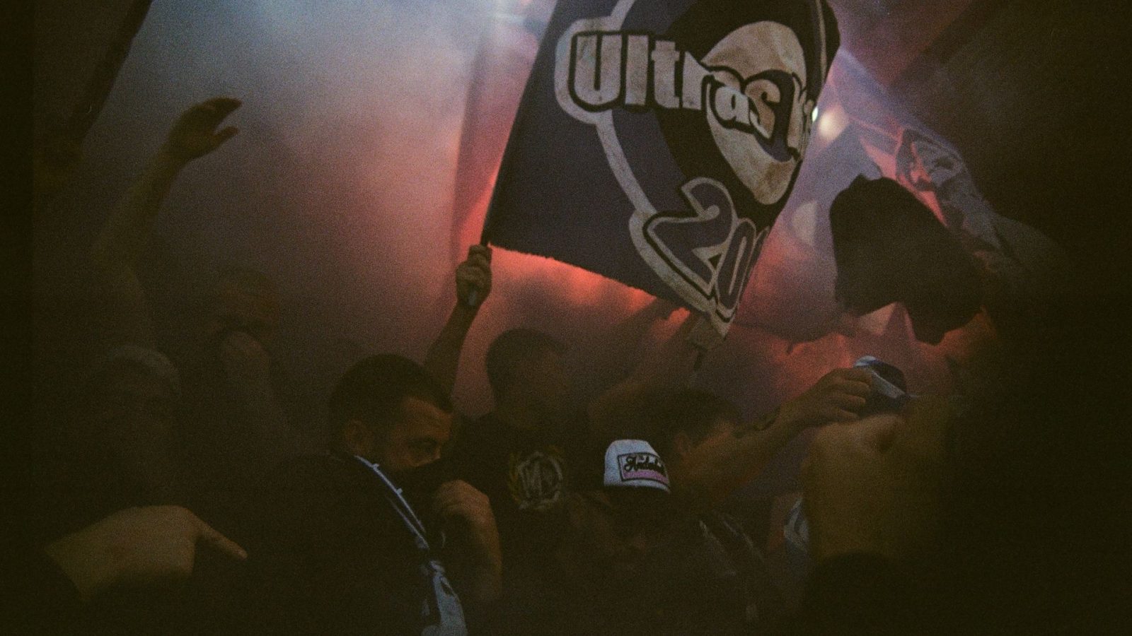 Fans mit Fackel und Ultras-Fahne in der Kurve